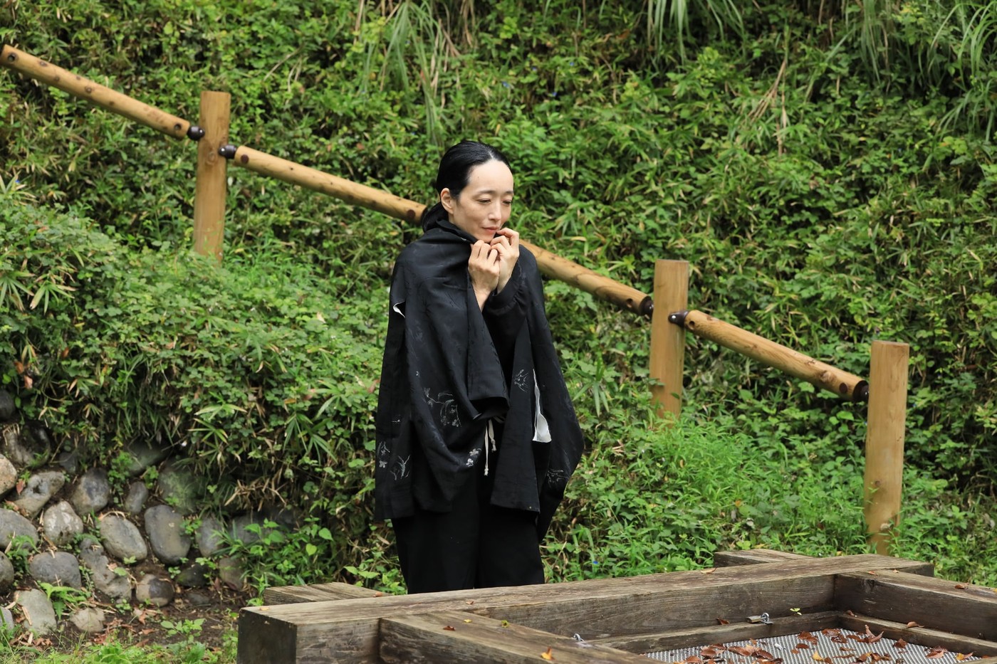 古い井戸のそばに佇む黒衣の女。作品の参考写真。